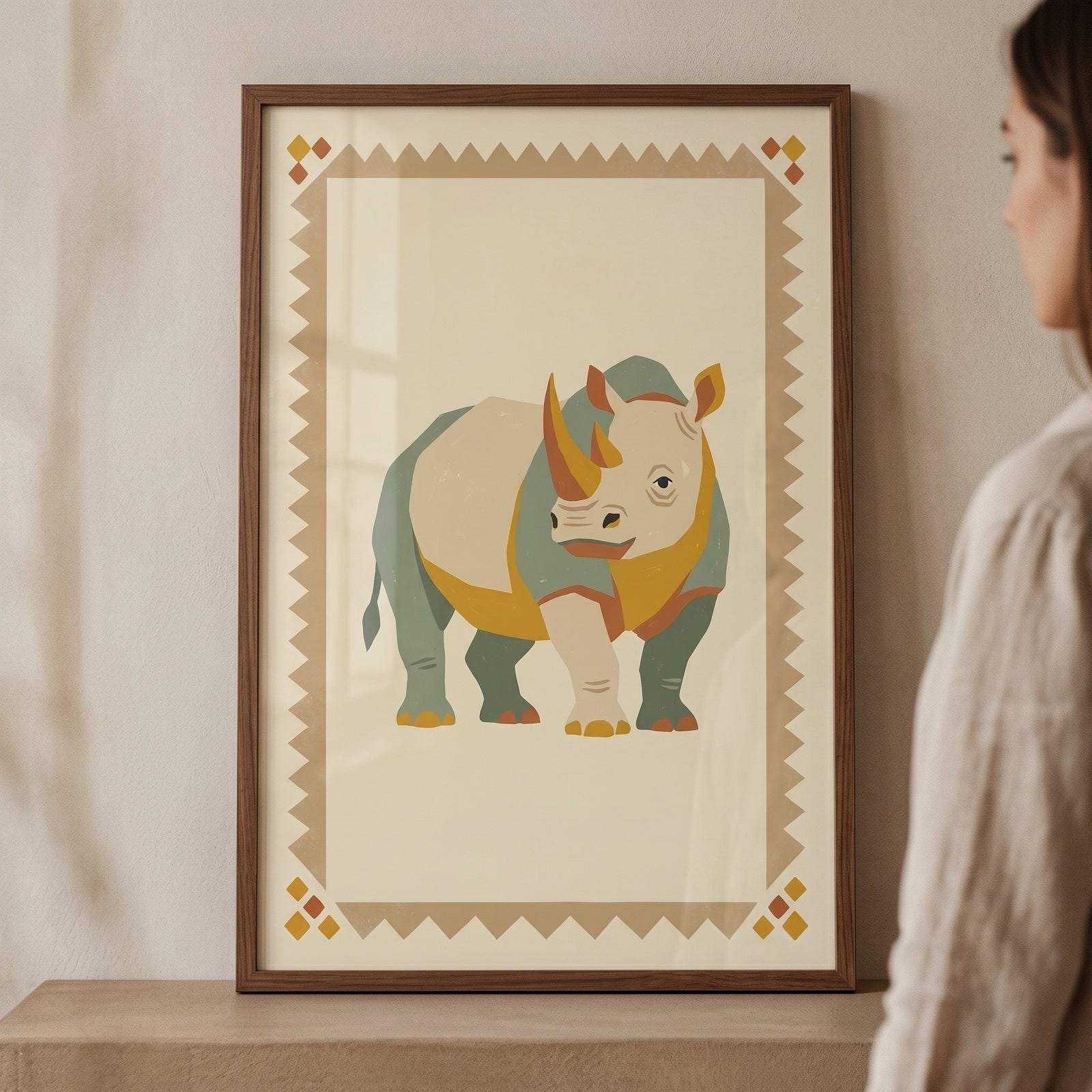 Sage green rhino artwork in a wood frame with a geometric border, displayed on a shelf next to a person.