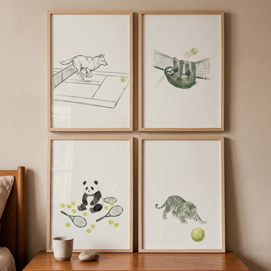 Sage green sporting animals wall art set of 4. Framed ink drawings of a wolf, sloth, panda, and tiger playing tennis.