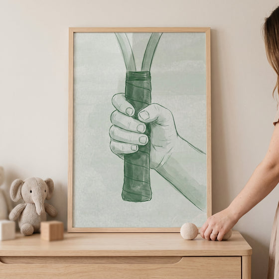 Framed sage green tennis wall art showing a hand gripping a racket above a wooden dresser with a plush elephant.
