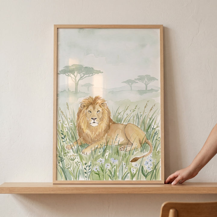 Framed savanna meadow lion wall art on a wooden shelf depicts a lion resting in tall grass with acacia trees behind.