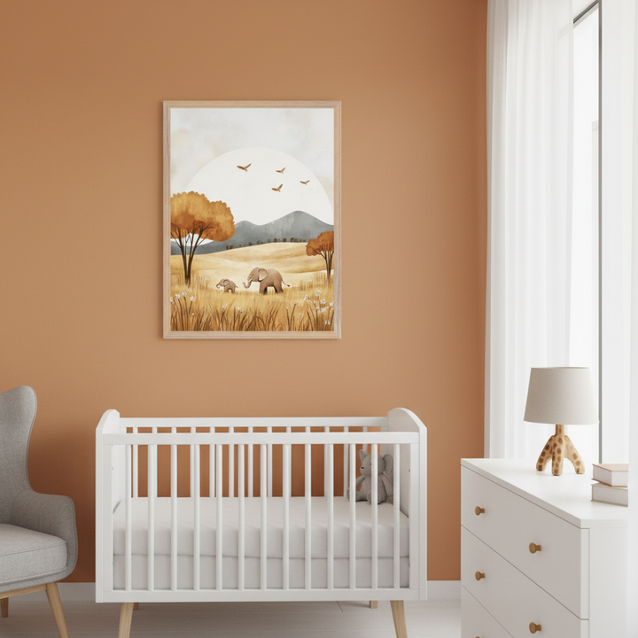Modern nursery with warm orange walls. A framed illustration of two elephants in a field with trees and mountains hangs above a white crib. A gray armchair is on the left, and a white dresser with a lamp is on the right.