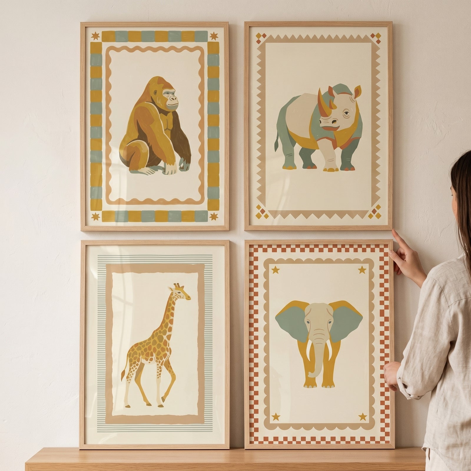 Woman hangs a scandi geometric safari animal wall art set of 4 featuring a gorilla, rhino, giraffe, and elephant.