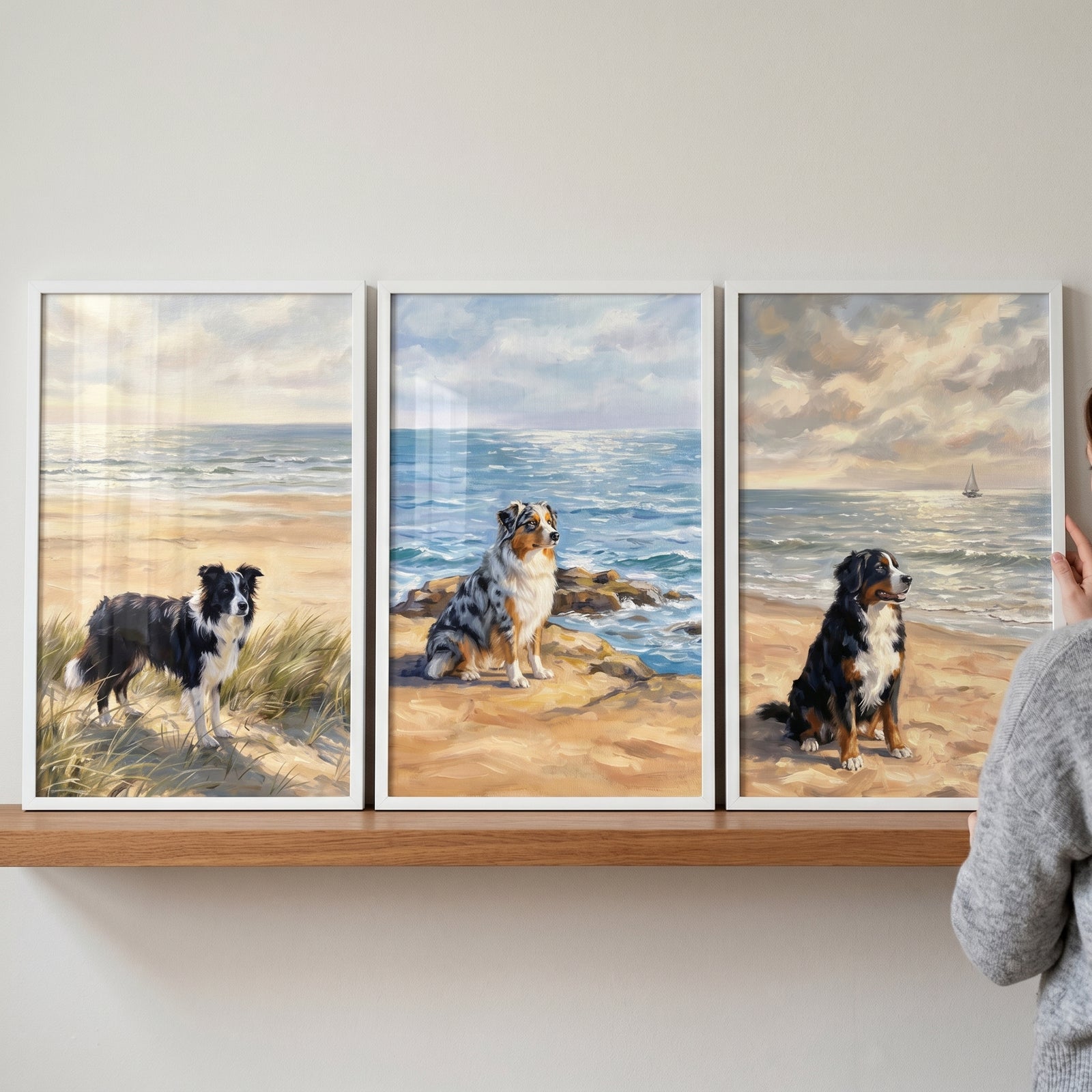 Scenic maritime coastal dog wall art set of 3 displays three dogs on beaches in white frames on a wooden shelf.