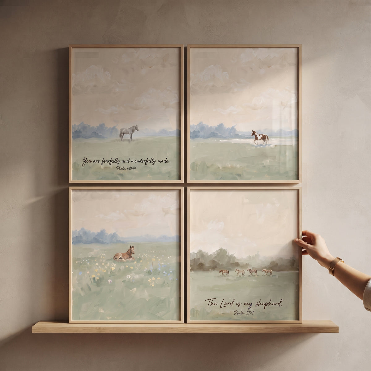 Scenic sage meadow horse wall art set of 4 with scripture verses on a wooden shelf being adjusted by a hand.
