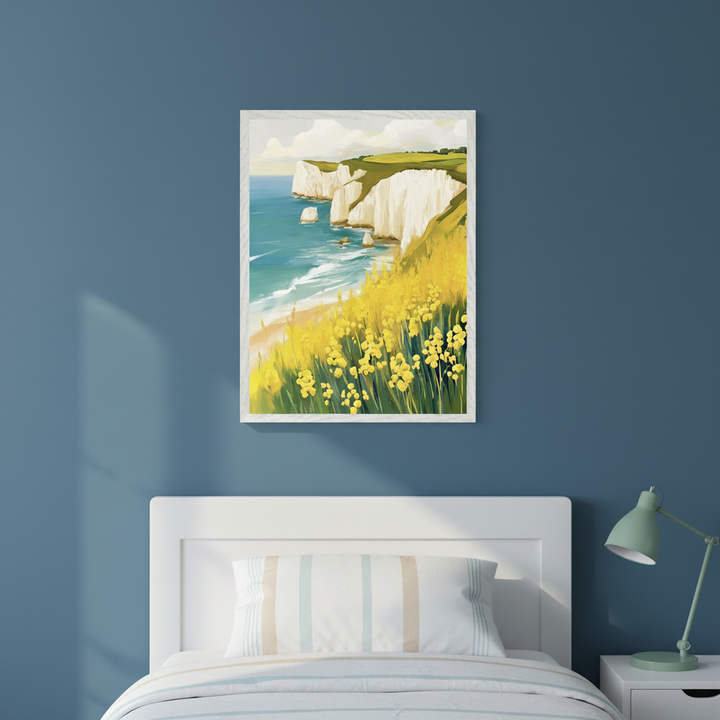 Modern bedroom with a white bed, striped bedding, and a white bedside table with a mint green lamp. A framed painting of a coastal landscape with white cliffs, a blue sea, and yellow wildflowers in a painterly style hangs on the blue wall above the bed.