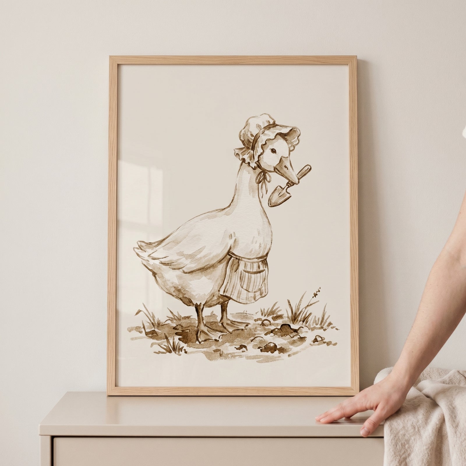 Sepia bonnet gardening goose wall art depicts a goose wearing an apron and bonnet while holding a trowel in its beak.