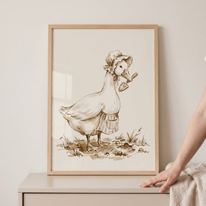 Sepia bonnet gardening goose wall art depicts a goose wearing an apron and bonnet while holding a trowel in its beak.