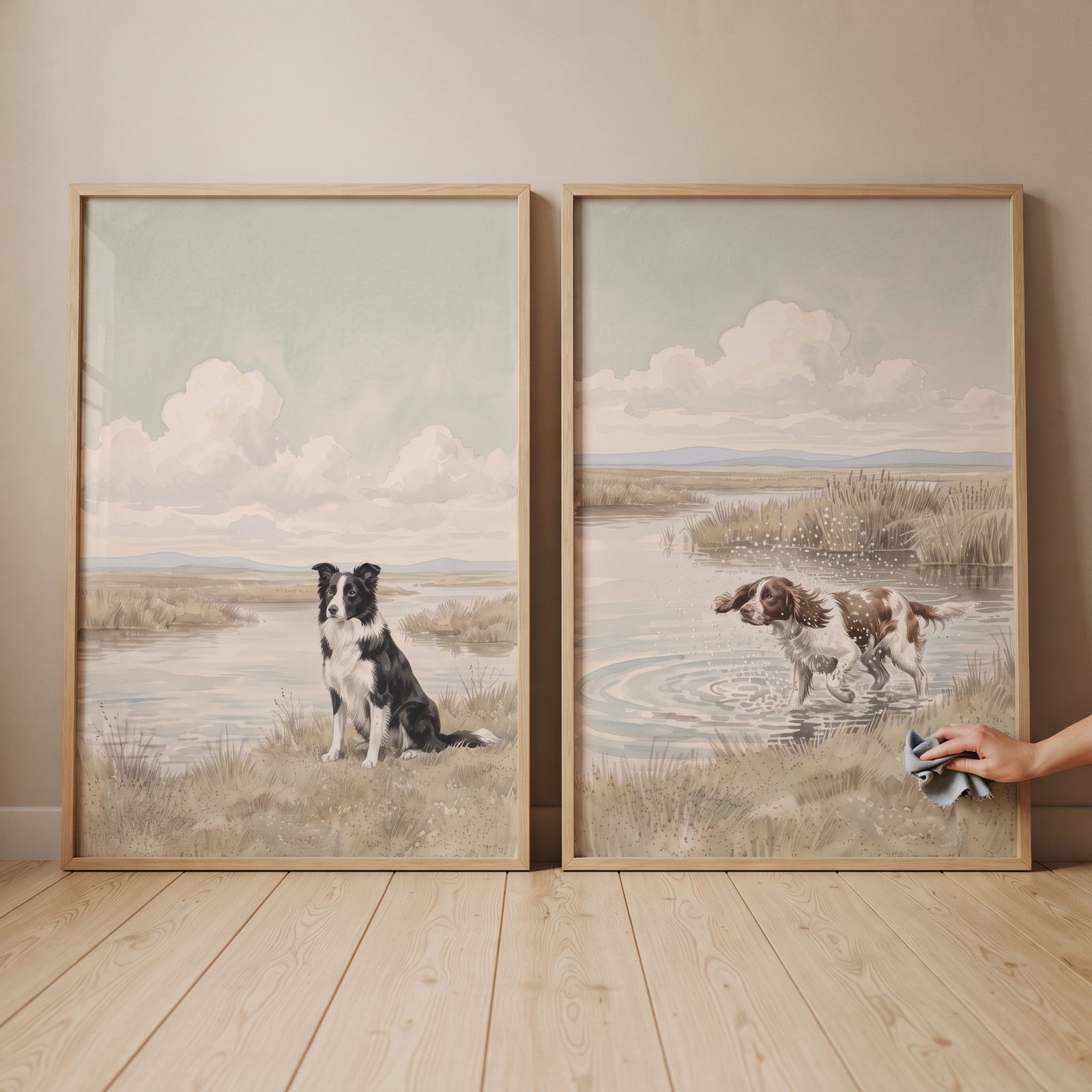Serene coastal marsh dog wall art set of 2 featuring dogs by water, as a hand wipes the frame with a cloth.