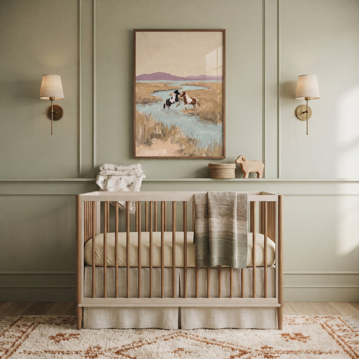 Green paneled nursery featuring a wooden crib and serene coastal marsh horses wall art between two wall sconces.