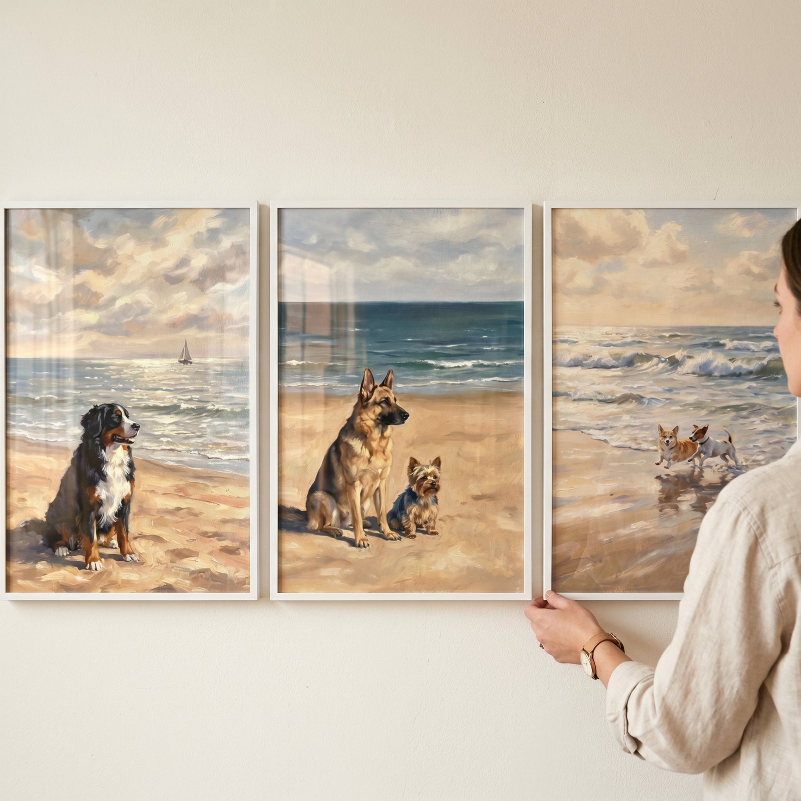 A person hanging a serene coastal shoreline dogs wall art set of 3 showing dogs on the sand and playing in ocean surf.