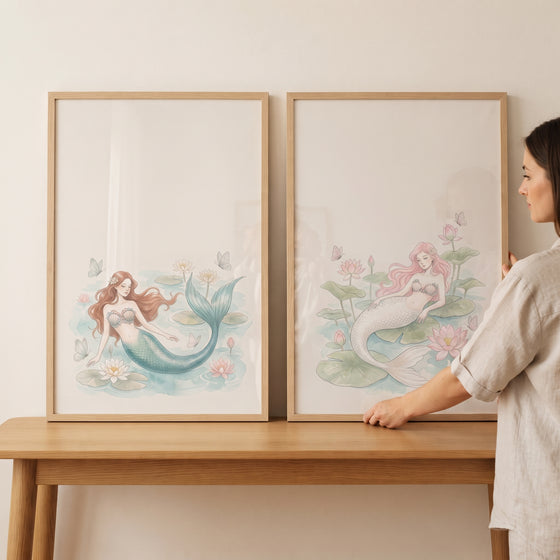 A woman adjusts a serene floating lotus mermaid wall art set of 2 in light wood frames resting on a wooden table.