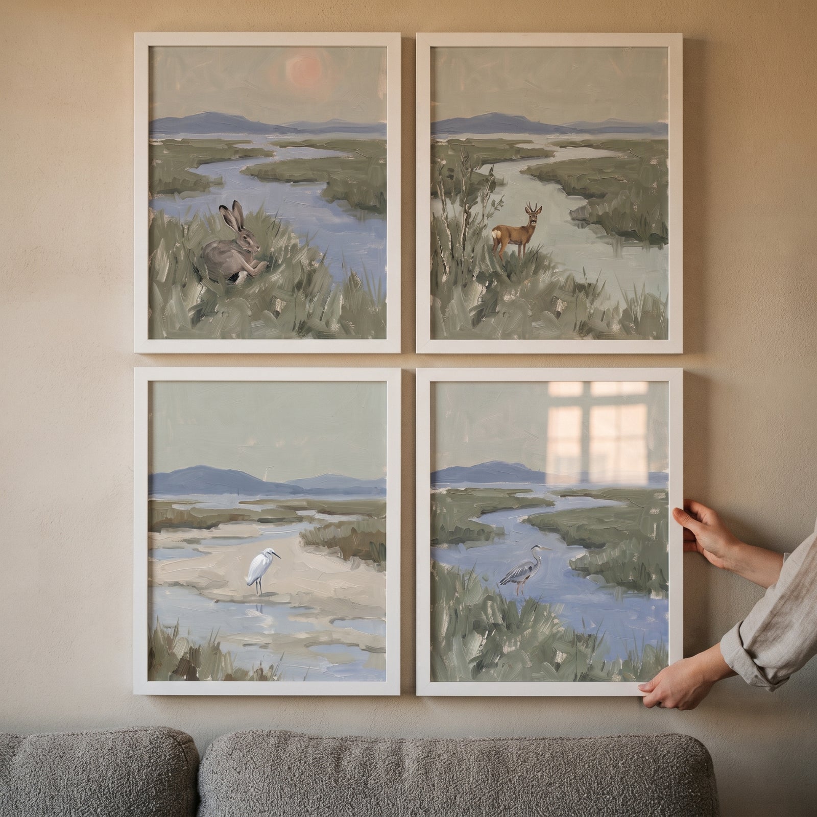 Serene green marsh animals wall art set of 4 features a hare, deer, and herons in landscape scenes above a grey couch.