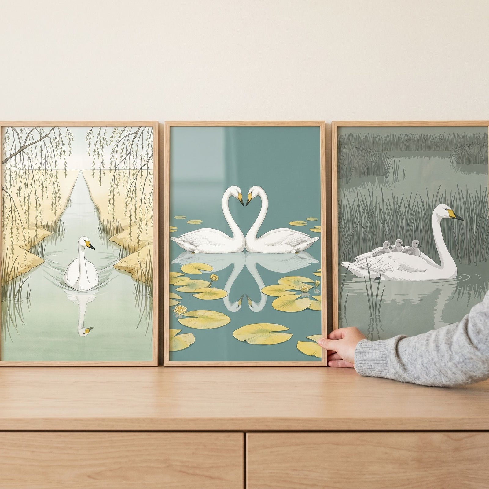 A serene sage white swan wall art set of 3 features birds near willow trees, lily pads, and reeds on a wood surface.