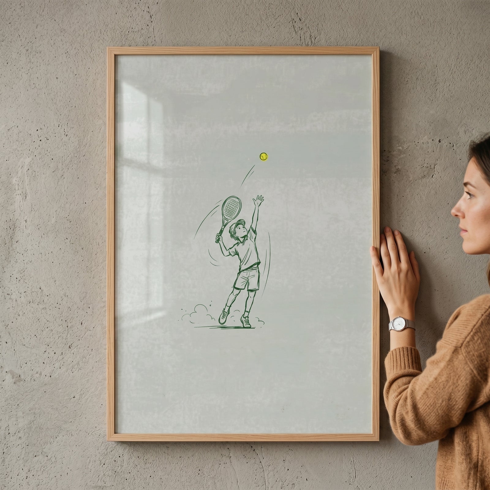 Serving ball tennis boy wall art in a wood frame hangs on a grey wall next to a woman.