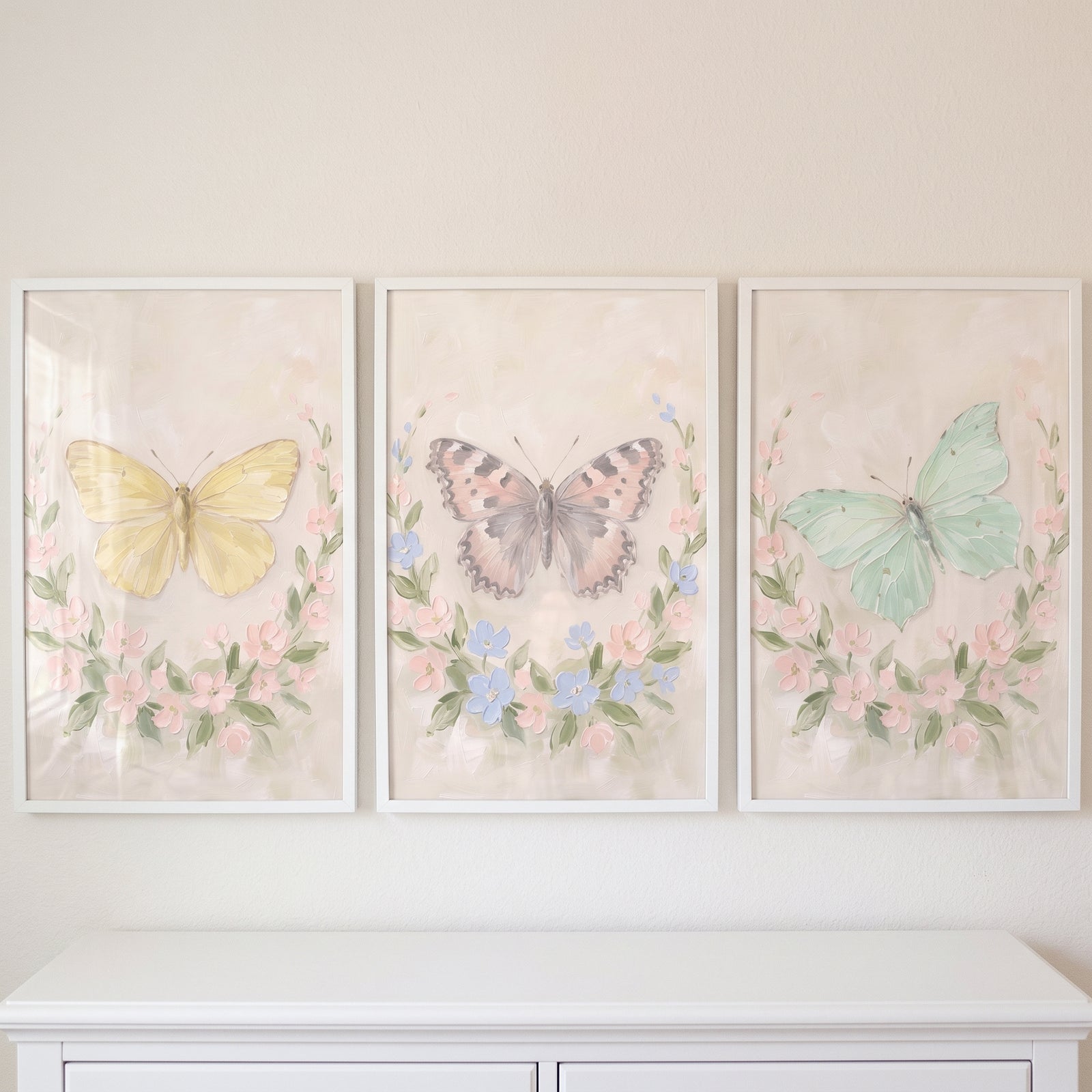 Shabby chic botanical butterfly wall art set of 3 with pastel butterflies and floral wreaths in white frames.