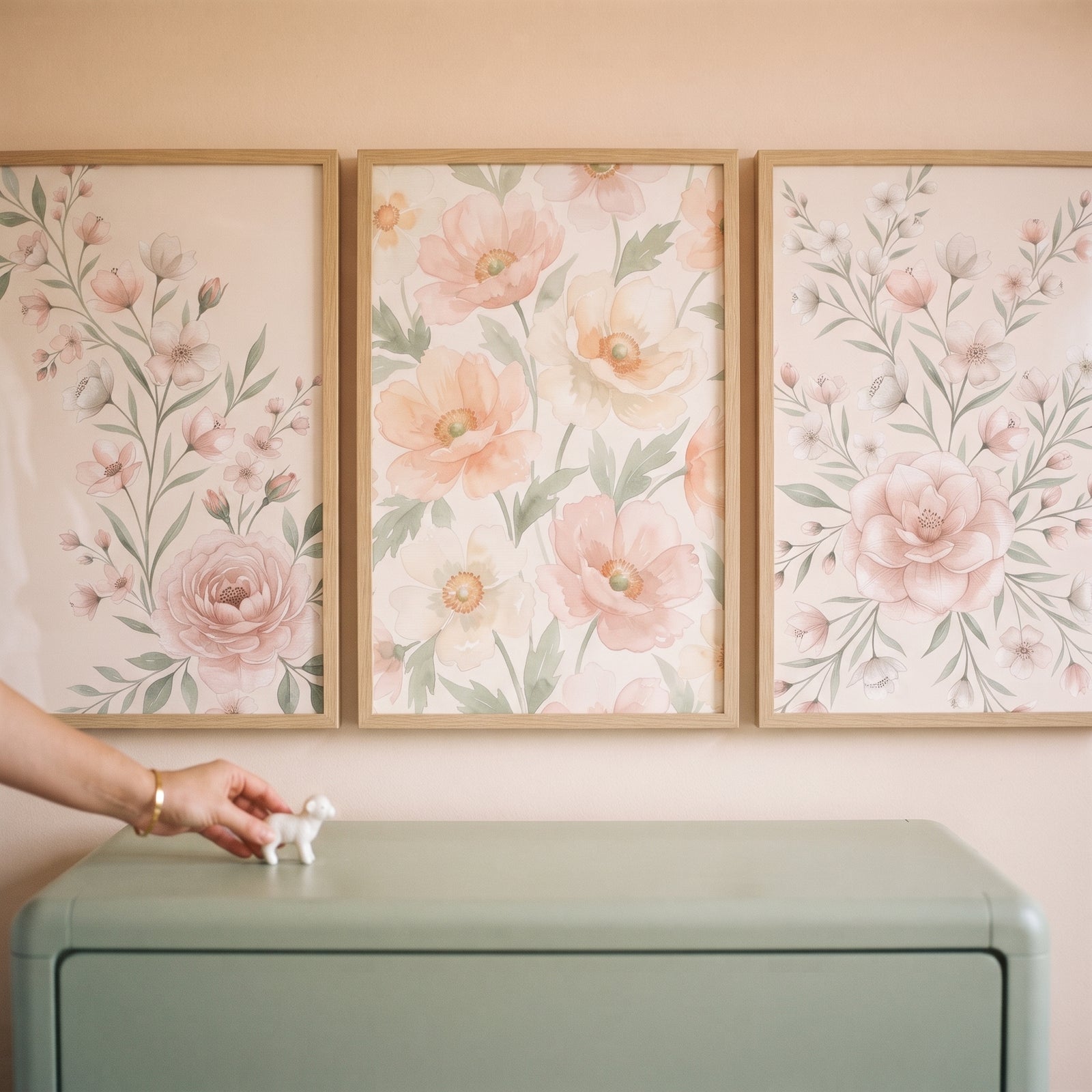 Shabby chic botanical floral wall art set of 3 above a green dresser as a hand places a small white animal figurine.