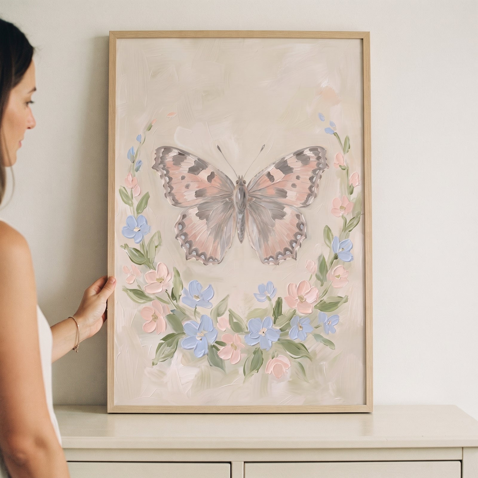 A woman holds framed shabby chic floral butterfly wall art featuring a butterfly and soft pastel floral wreath.