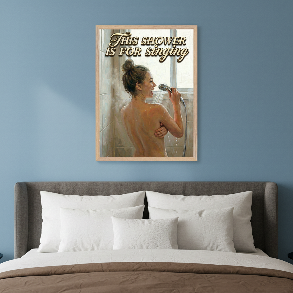 Modern bedroom with a gray upholstered bed and white pillows. A framed oil painting of a woman singing in the shower, holding the shower head like a microphone, hangs above the bed. Text: "THIS SHOWER IS FOR singing".