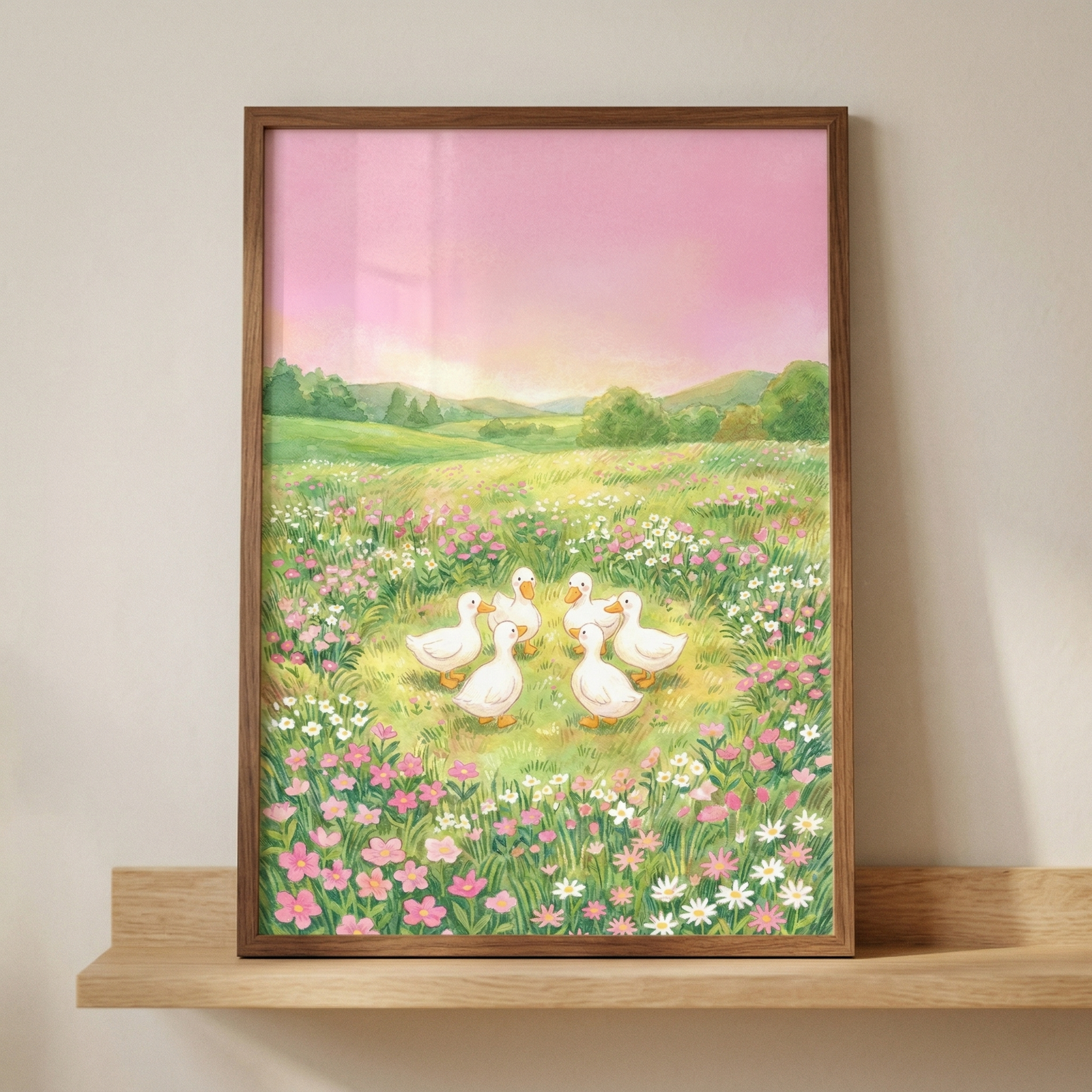 A vertical rectangular piece of artwork housed in a slim wood frame, resting on a light-colored wooden shelf against a plain, neutral wall. The illustration features a group of six white ducks gathered in a circle within a vibrant meadow. The field is filled with a variety of small pink and white wildflowers and lush green grass. In the background, rolling green hills and soft tree silhouettes sit beneath a hazy, pastel pink and light purple sky, evoking a serene sunset or dawn. 