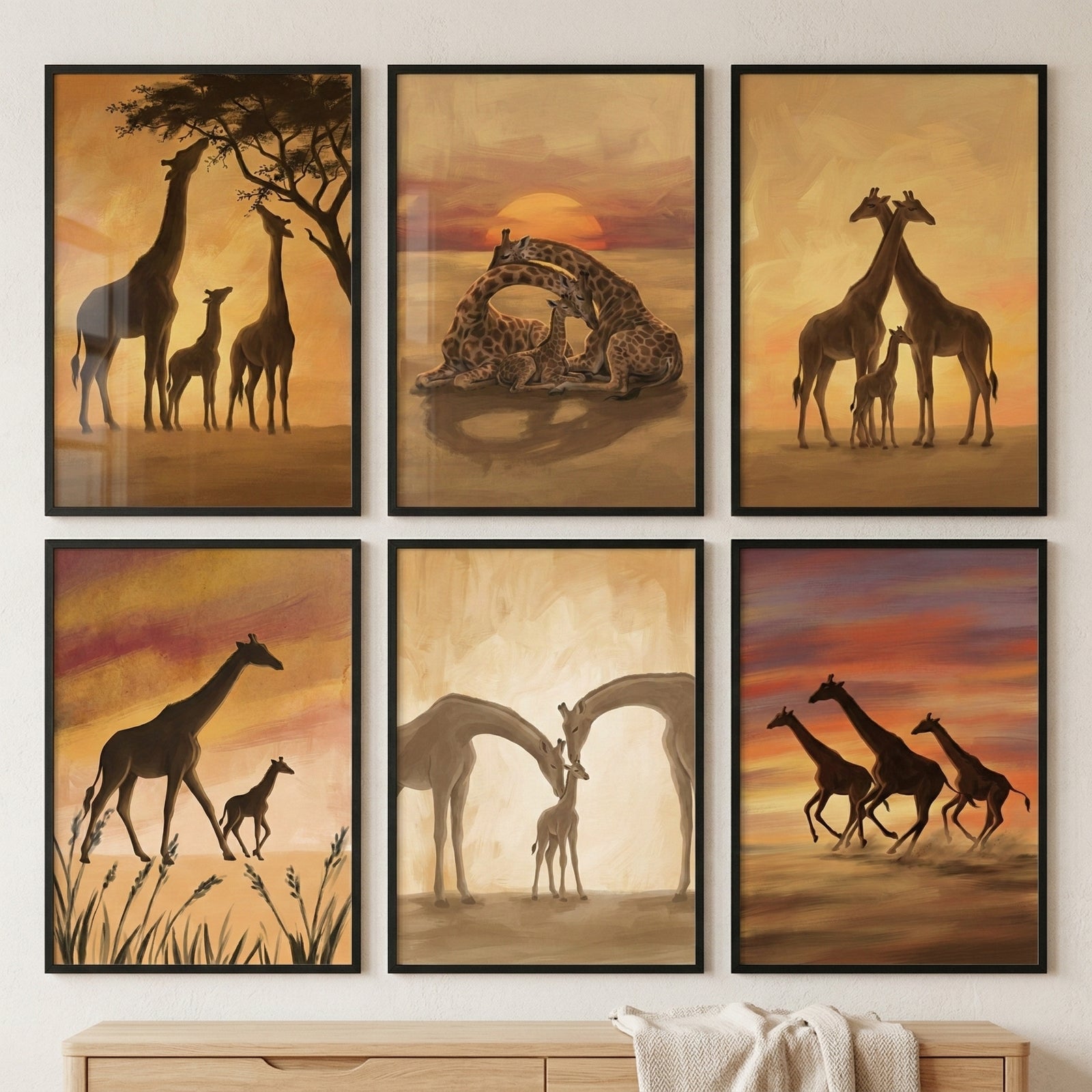 Six framed giraffe themed paintings arranged in two rows hang above a wooden dresser with a soft blanket draped across it. The artworks show warm sunset scenes including giraffe families standing together with calves, a pair of giraffes bending toward a young calf, a giraffe walking beside a baby through tall grass, and three giraffes running across a dusty landscape. The paintings use soft golden and orange tones that create a calm safari inspired nursery wall display.