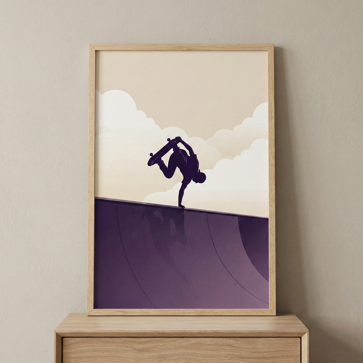 A framed minimalist illustration depicts the dark silhouette of a skateboarder performing a handplant trick on the edge of a curved purple ramp. Above, stylized clouds float in a cream sky. A subtle reflection of the figure is visible on the ramp's surface. The entire scene uses a simple purple and off-white color palette. This artwork is presented in a light-toned wooden frame, resting on a matching wooden surface against a neutral, flat-colored wall.