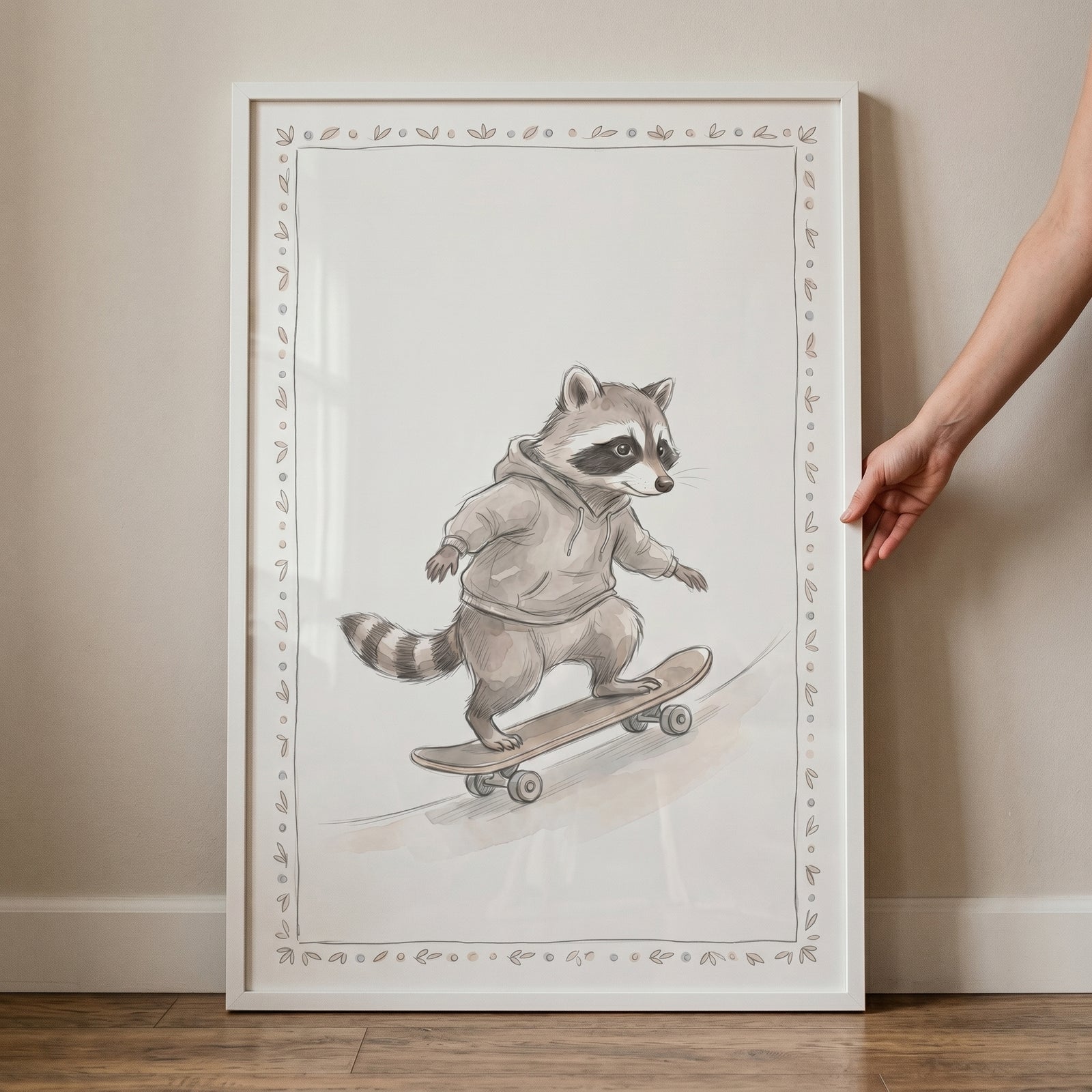 White framed skateboarding grey hoodie raccoon wall art illustration held against a neutral wall.