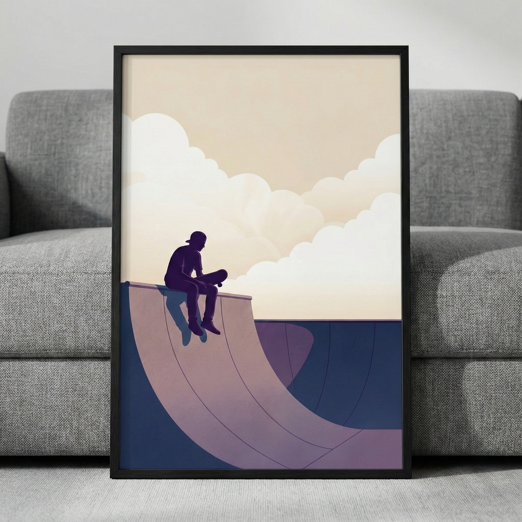 A minimalist digital illustration featuring the silhouette of a person sitting on the edge of a curved skate park ramp. The individual is shown in profile, looking out over the structure. The composition uses a soft color palette of purple, blue, and cream. Large, stylized clouds billow in a warm, light sky behind the figure. The artwork is presented in a simple black frame, leaning against a grey fabric sofa. The overall mood is peaceful and reflective.
