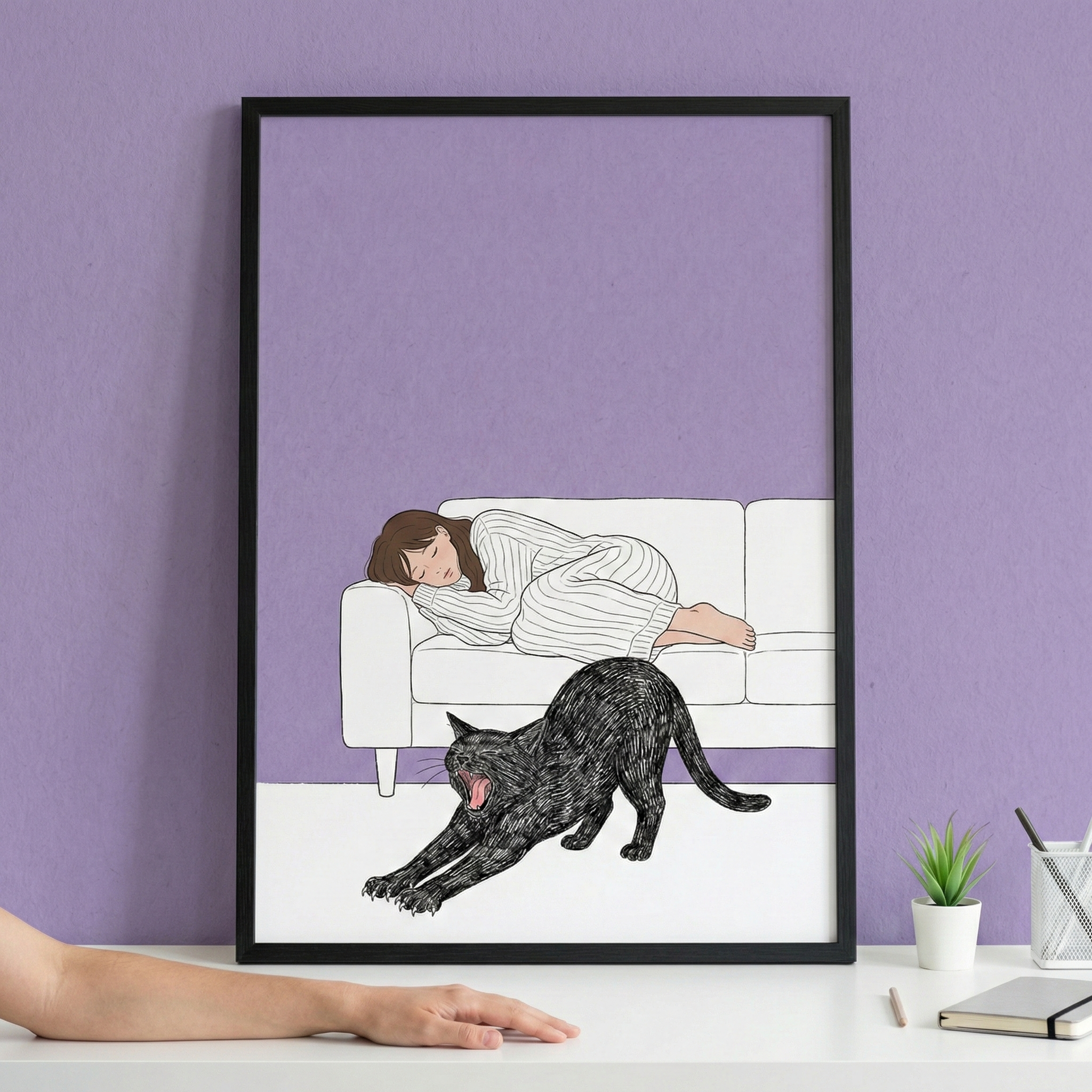 A minimalist framed illustration rests on a white desk against a textured purple wall. Within the artwork, a woman with brown hair in a striped nightgown sleeps on a white sofa. In the foreground, a large, textured black cat stretches and yawns on a white floor against a solid lavender background. On the desk, a person's arm reaches from the left, while a small potted succulent, a pen holder, and a notebook sit to the right of the black frame.