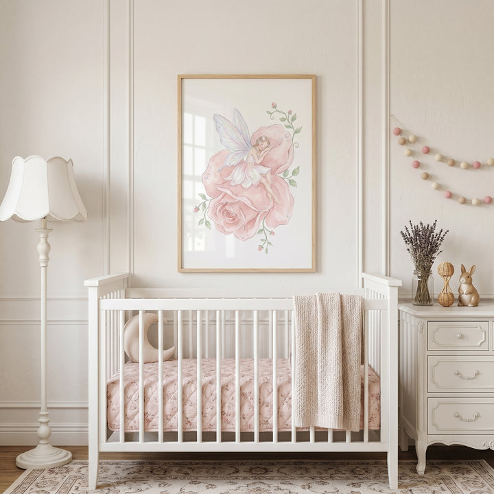 Sleeping pink rose fairy wall art hangs above a white crib with pink bedding, a floor lamp, and a white dresser.