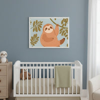 Modern nursery with a white crib, wooden dresser, and sloth nightlight against a blue-gray wall. A framed art print of a cartoon sloth on a branch hangs above the crib, which contains a stuffed sloth and a green blanket.