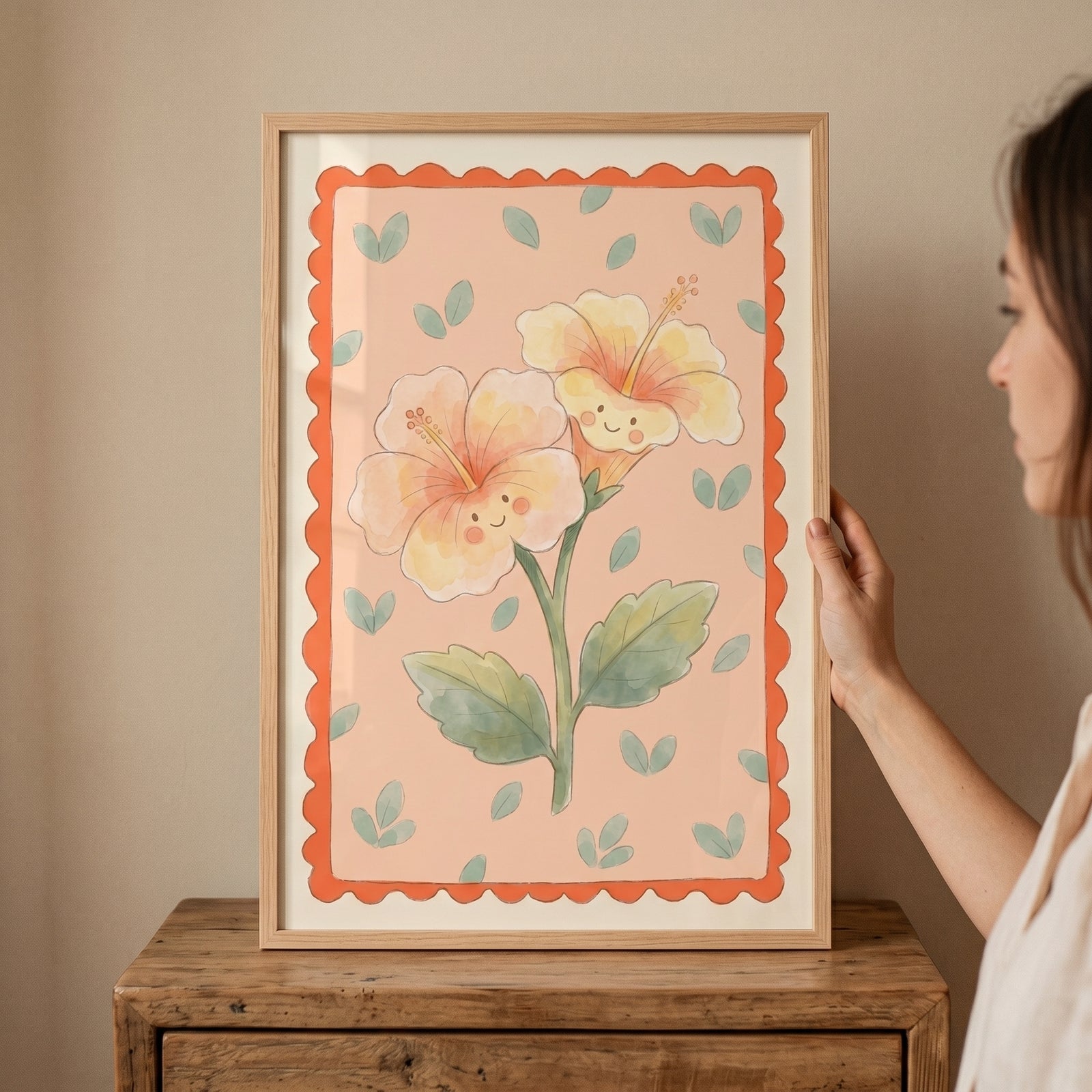 Smiley face yellow hibiscus flower wall art on a pink backdrop with a scalloped orange border and light wood frame.