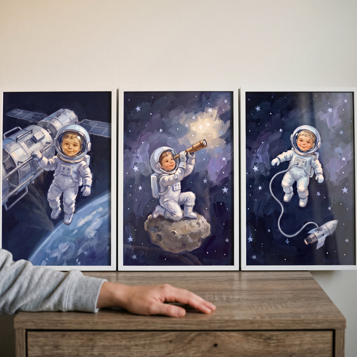 Smiling face baby astronaut wall art set of 3 shows a child near a space station, using a telescope, and with a rocket.