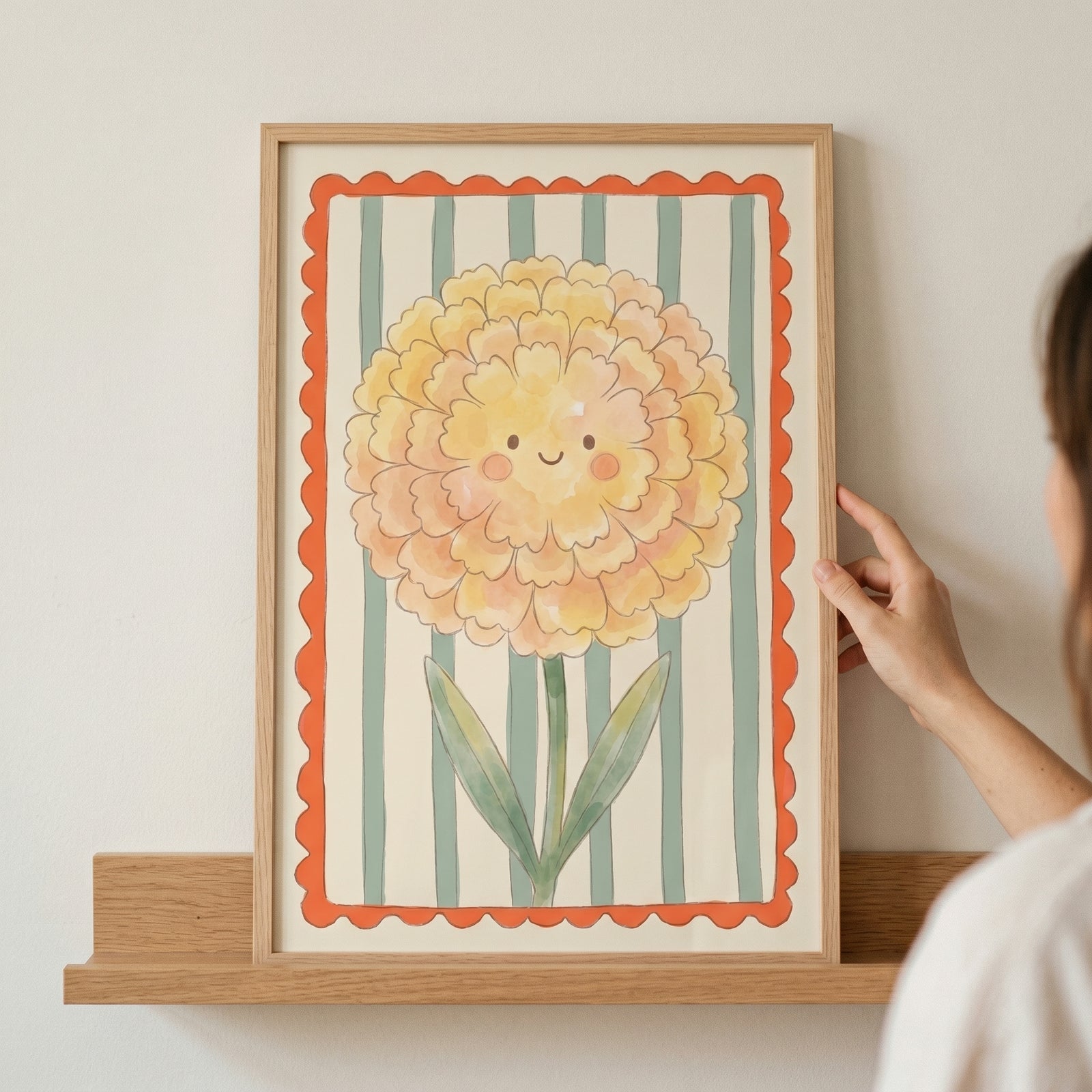Smiling yellow marigold flower wall art with a cute face and teal stripes in a light wood frame on a shelf.