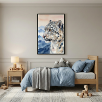A cozy bedroom features a light wood bed with soft blue bedding and a gray knit blanket. A framed painting of a snow leopard against a mountain backdrop hangs on the wall. A wooden nightstand with a lamp and toys sits beside the bed, and wooden blocks are scattered on a patterned rug.
