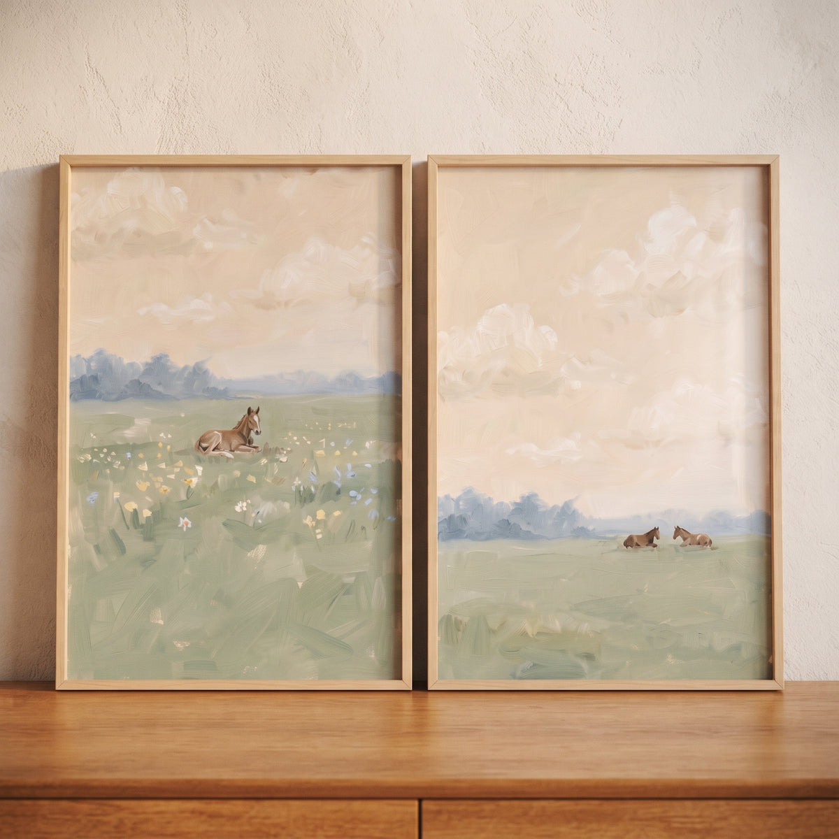 Framed soft apricot sky horse artwork set of 2 rests on a wooden dresser against a neutral textured wall.