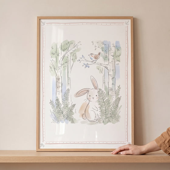 Watercolor illustration of a soft birch tree bunny wall art in a wooden frame featuring a bird, ferns, and tall trees.