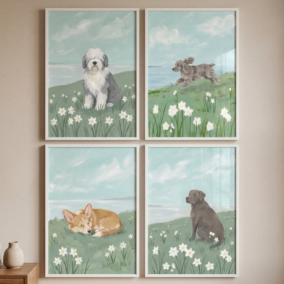 soft blue coastal dog wall art set of 4 with a sheepdog, jumping poodle, sleeping corgi, and sitting lab in meadows.