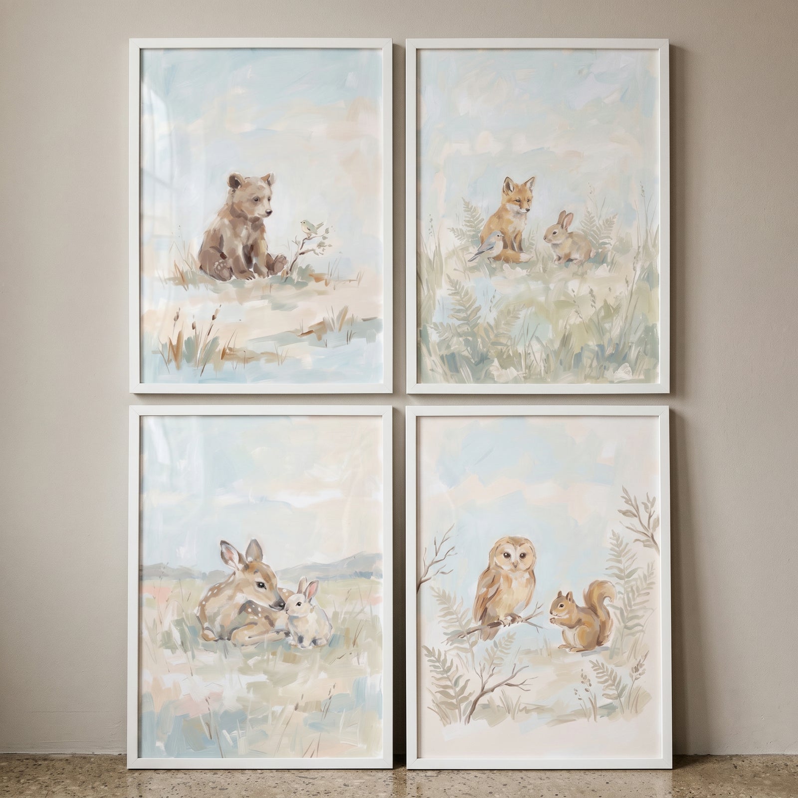 Soft blue woodland animals wall art set of 4 with a bear, fox, deer, owl, bunnies, and a squirrel in white frames.