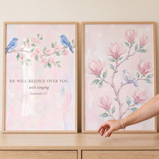 Soft blush botanical bird wall art set of 2 with blue birds, pink magnolia blossoms, and a Zephaniah 3:17 Bible verse.