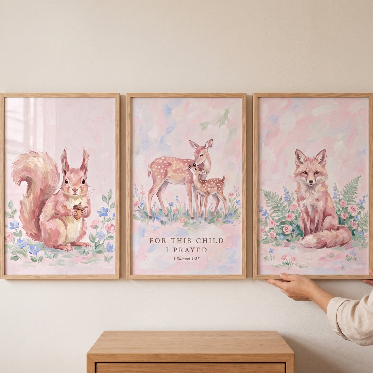 Soft blush forest animals print set of 3 featuring a squirrel, deer, and fox in light wood frames on a neutral wall.