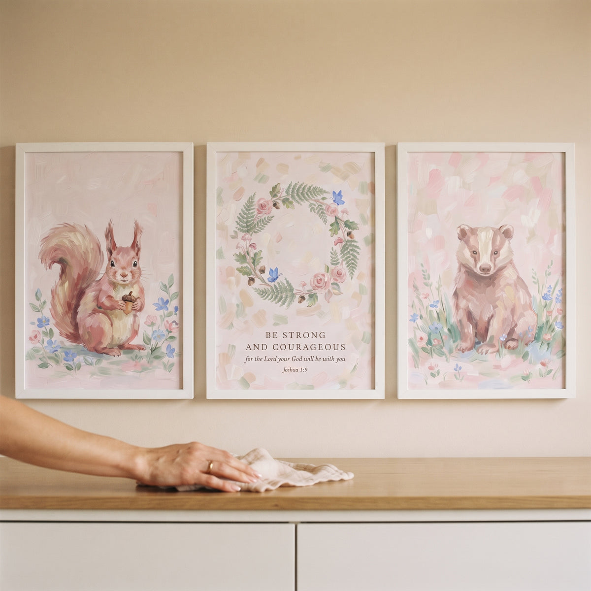 A soft blush pink nature wall art set of 3 featuring a squirrel, a badger, and a floral wreath with a scripture verse.