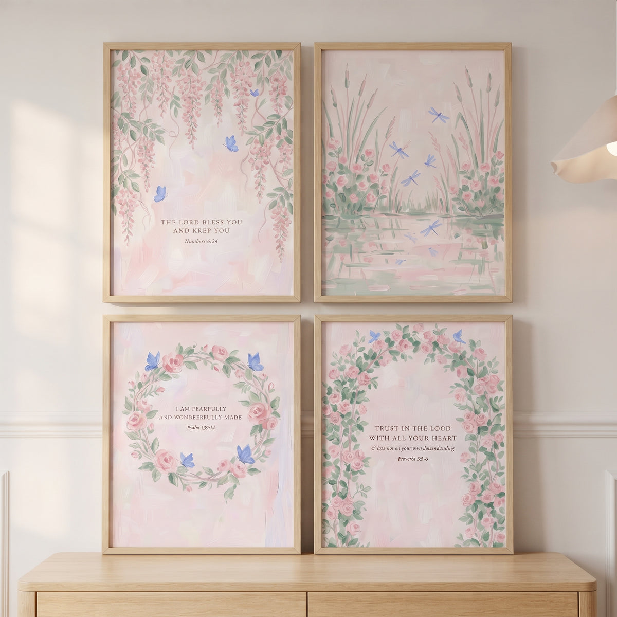 Soft blush watercolor nature wall art set of 4 with floral designs and Bible verses in light wood frames above a dresser.