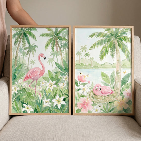 Soft botanical pink flamingo wall art set of 2 depicts birds among tropical palm trees and flowers in wood frames.