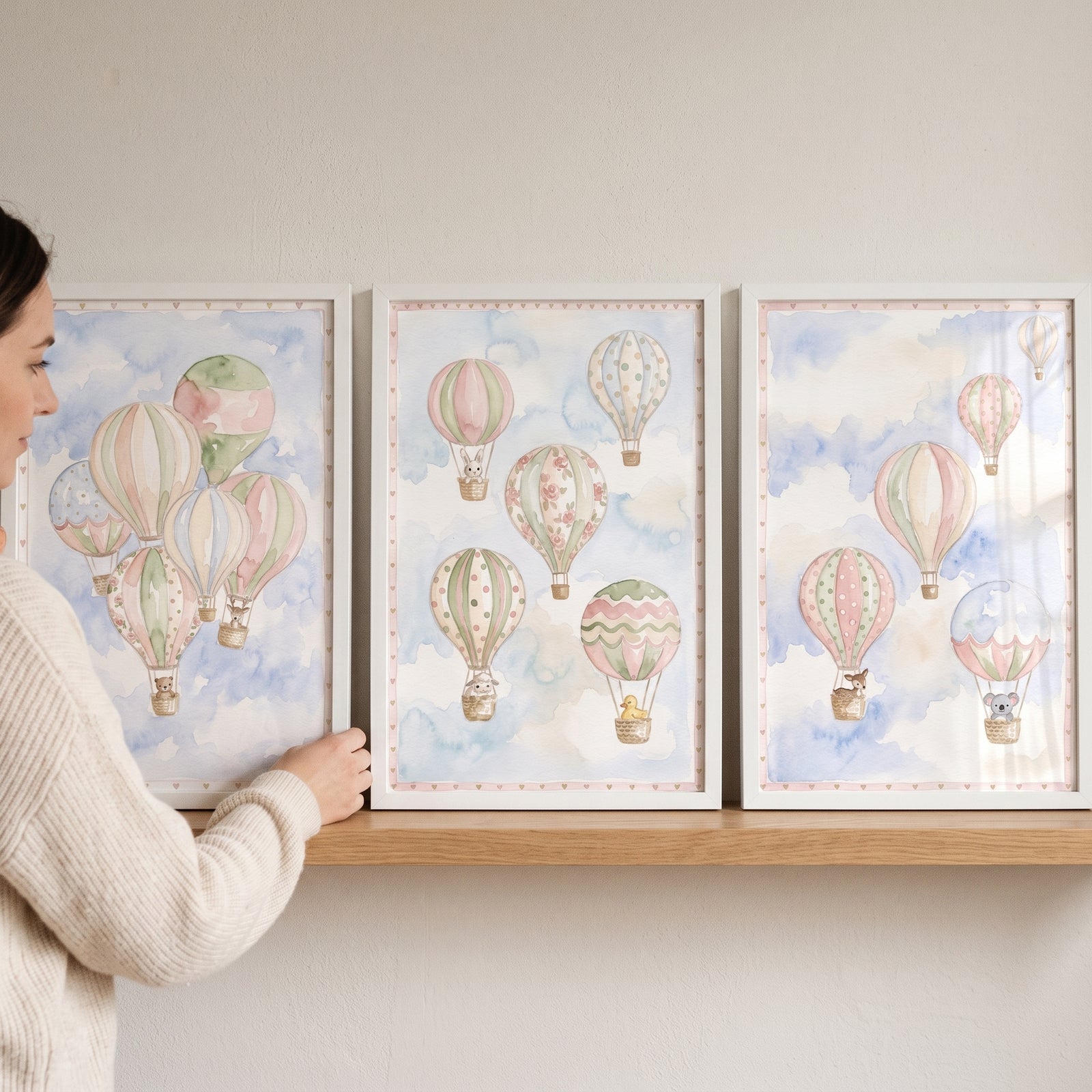 A woman places a soft clouds animal balloon wall art set of 3 featuring cute animals in baskets on a wooden shelf.