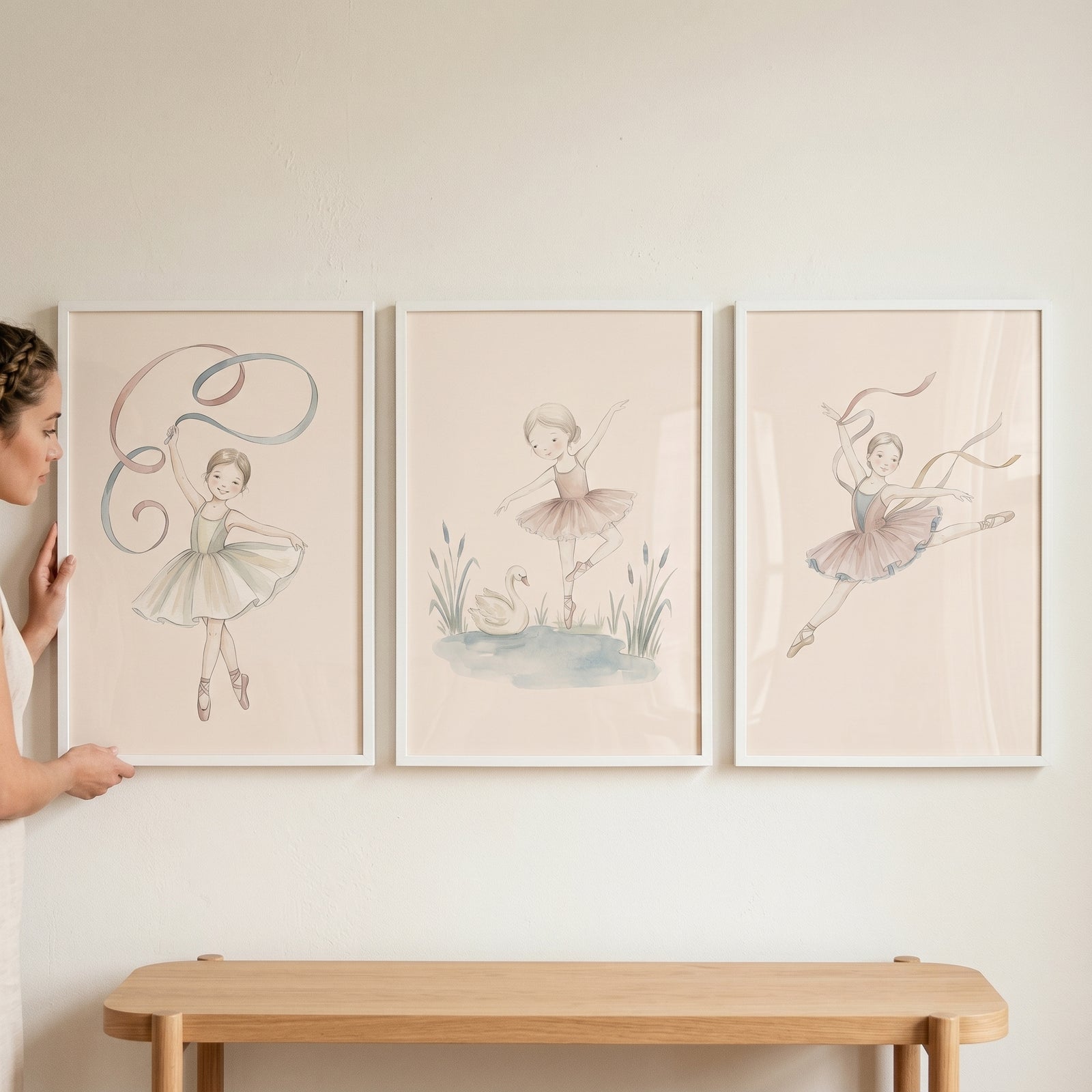Soft cream watercolor ballerina wall art set of 3 featuring dancers in tutus hanging on a wall above a wooden bench.
