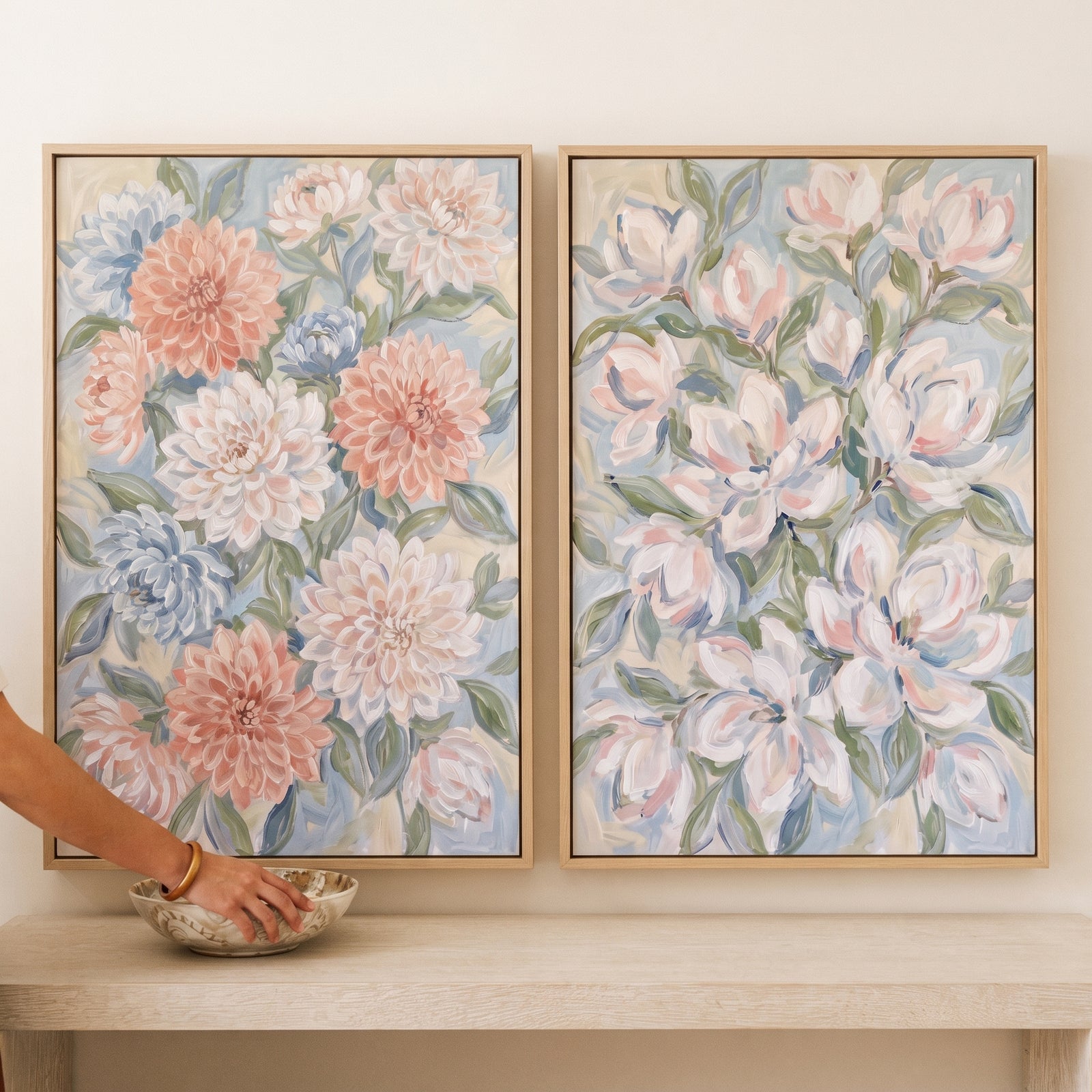 Two soft impressionist garden floral wall art set of 2 in light wood frames hang above a neutral console table.