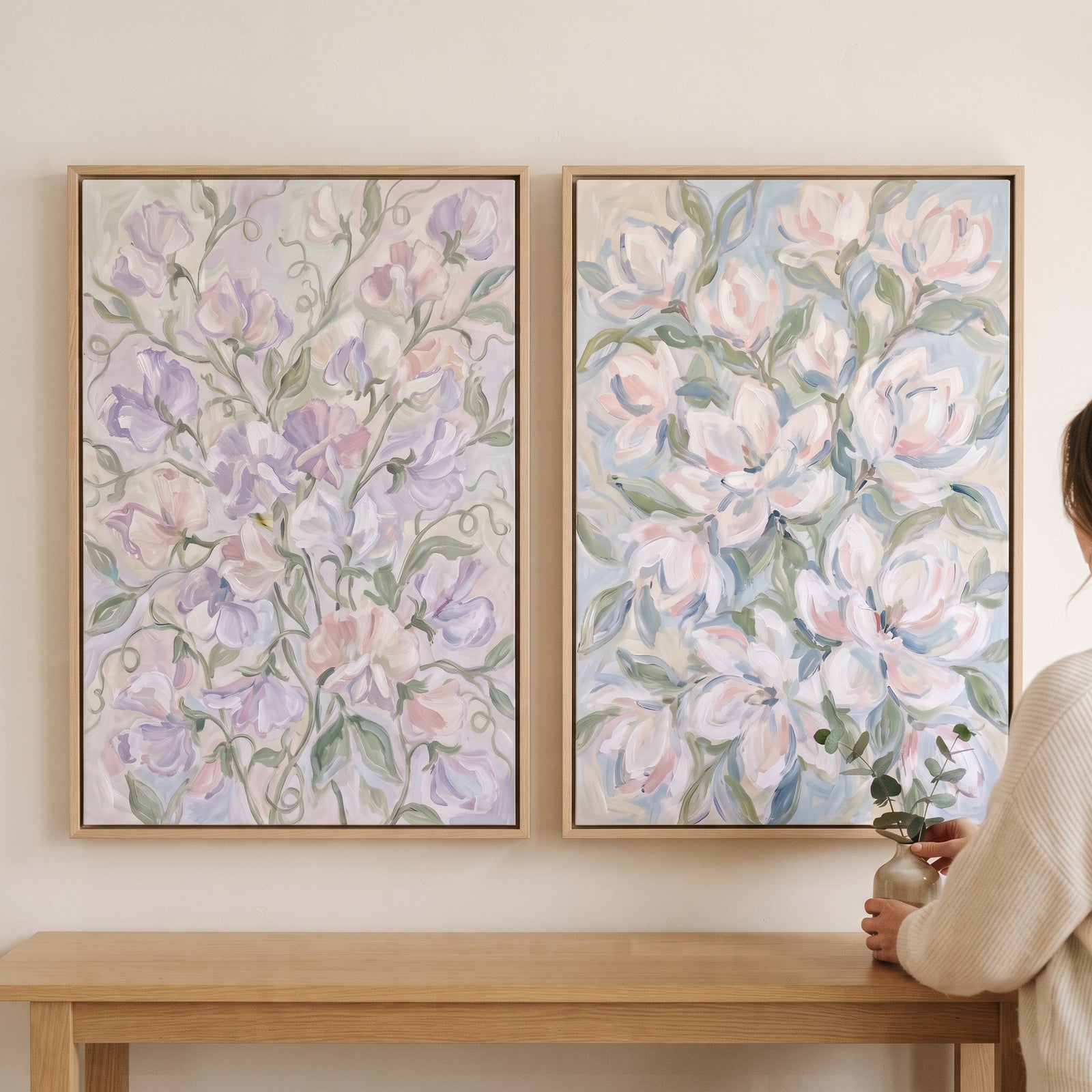 Soft lavender botanical floral wall art set of 2 in light wood frames hung on a neutral wall above a wooden table.