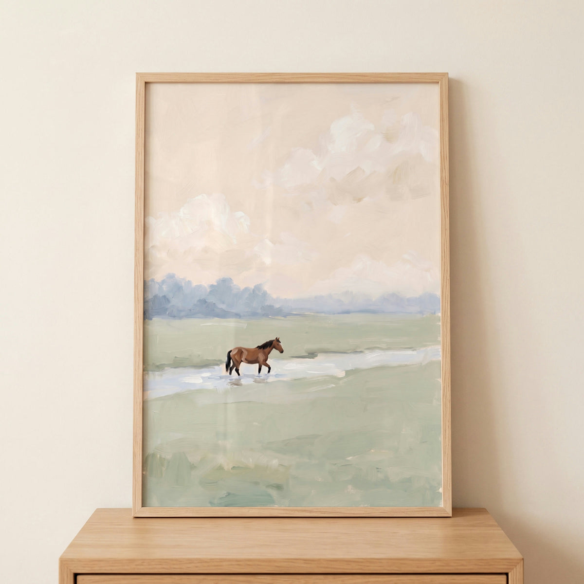 Soft meadow brown horse wall art in a light wood frame features a lone horse crossing water in a muted landscape.