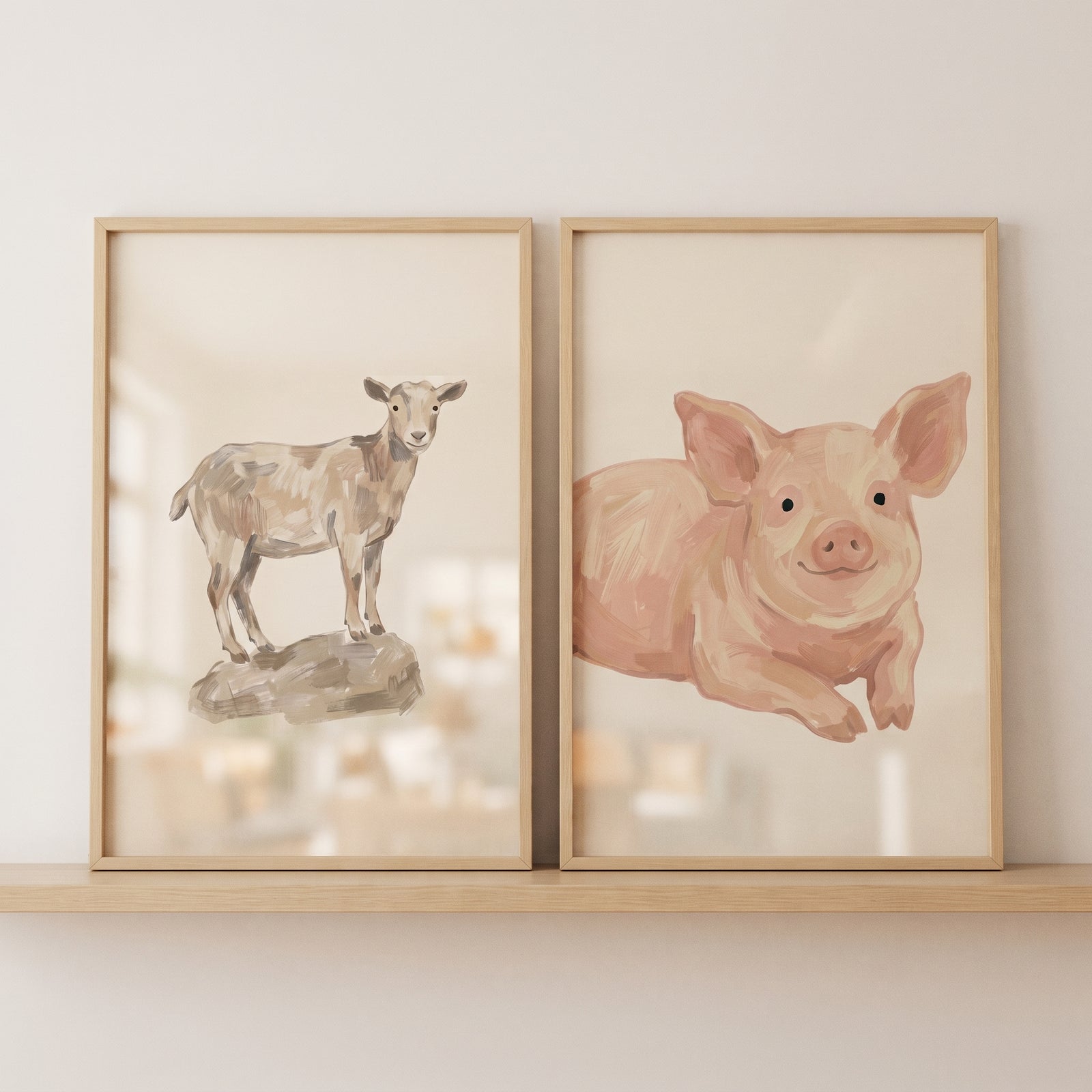 Soft neutral farm animals wall art set of 2 with a goat on a rock and a pig in light wood frames on a shelf.