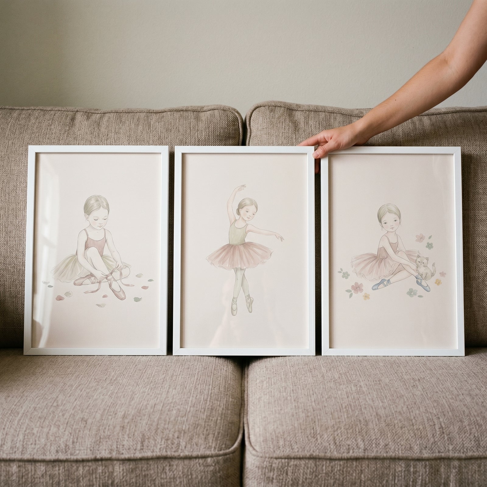 Soft neutral girl ballerina wall art set of 3 includes three white-framed sketches leaning against a tan couch.
